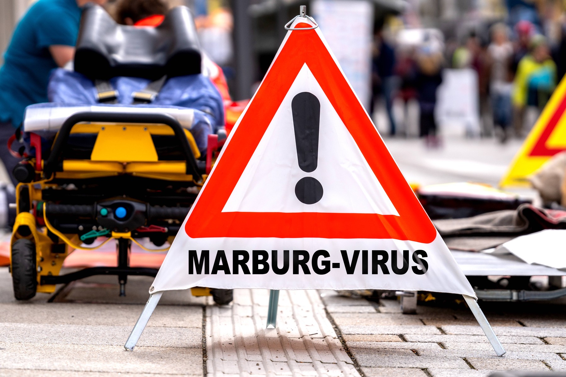 Germany - October 3, 2024: Warning sign: Marburg virus, in front of emergency paramedics on a street. Symbolic image of the dangerous virus spreading and infecting others. PHOTOMONTAGE *** Warnschild: Marburg-Virus, vor Notfallsanitätern auf einer Straße. Symbolbild Notfall und Ansteckung des gefährlichen Virus. FOTOMONTAGE,Image: 915611711, License: Rights-managed, Restrictions: imago is entitled to issue a simple usage license at the time of provision. Personality and trademark rights as well as copyright laws regarding art-works shown must be observed. Commercial use at your own risk., Model Release: no, Credit line: Michael Bihlmayer / imago stock&people / Profimedia