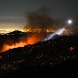 The light of a fire fighting helicopter illuminates a smouldering hillside as the Palisades fire grows near the Mandeville Canyon neighborhood and Encino, California, on January 11, 2025. The Palisades Fire, the largest of the Los Angeles fires, spread toward previously untouched neighborhoods January 11, forcing new evacuations and dimming hopes that the disaster was coming under control. Across the city, at least 11 people have died as multiple fires have ripped through residential areas since January 7, razing thousands of homes in destruction that US President Joe Biden likened to a "war scene.",Image: 953067535, License: Rights-managed, Restrictions: , Model Release: no, Credit line: Patrick T. Fallon / AFP / Profimedia