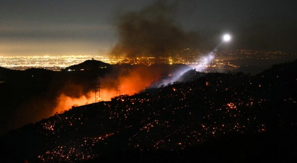 The light of a fire fighting helicopter illuminates a smouldering hillside as the Palisades fire grows near the Mandeville Canyon neighborhood and Encino, California, on January 11, 2025. The Palisades Fire, the largest of the Los Angeles fires, spread toward previously untouched neighborhoods January 11, forcing new evacuations and dimming hopes that the disaster was coming under control. Across the city, at least 11 people have died as multiple fires have ripped through residential areas since January 7, razing thousands of homes in destruction that US President Joe Biden likened to a "war scene.",Image: 953067535, License: Rights-managed, Restrictions: , Model Release: no, Credit line: Patrick T. Fallon / AFP / Profimedia